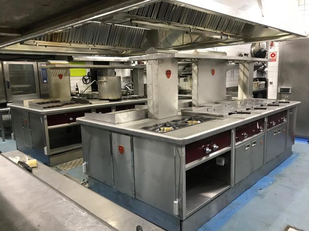 Cocina profesional equipada con múltiples fogones y campanas extractoras.