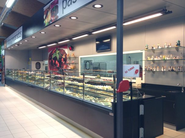 Mostrador de pastelería con vitrina y variedad de productos dulces.