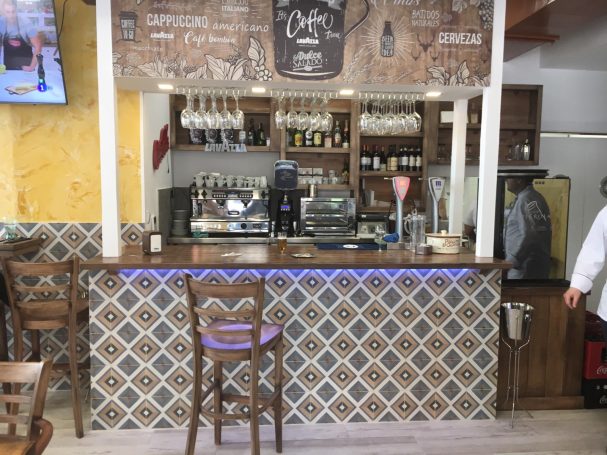 Barrra de un restaurante con decoración rústica y azulejos coloridos.