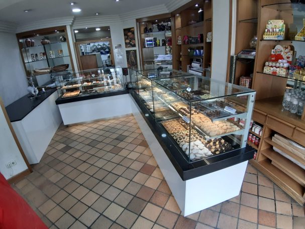 Interior de una tienda con vitrinas de exhibición y estanterías llenas de productos.