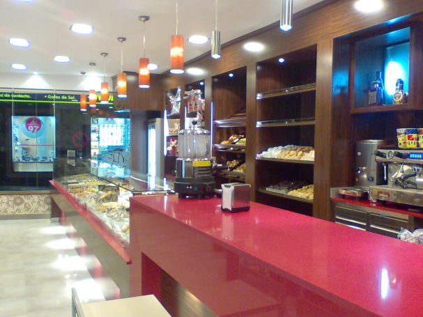 Interior de una pastelería con mostrador rosa y estanterías llenas de dulces.