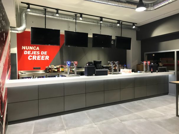 Mostrador moderno con varias pantallas y decoración en rojo. Ambiente industrial.