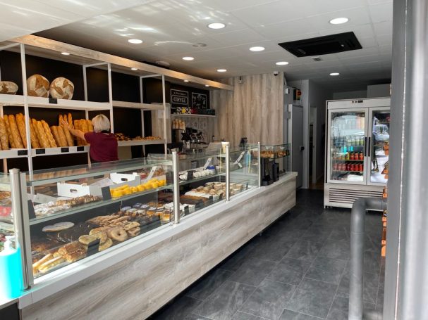 Panadería con estanterías de panes y dulces, iluminación brillante y área de ventas.