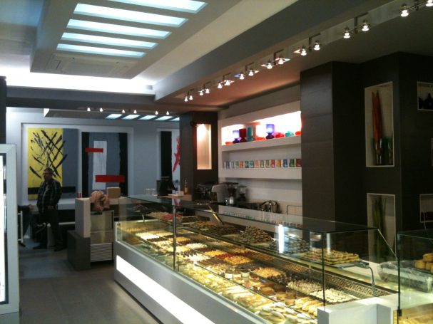 Pastelería moderna con vitrinas de postres y decoración minimalista en tonos claros.