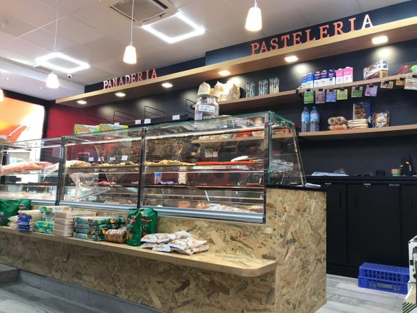 Mostrador de una pastelería con productos expuestos y estanterías al fondo.