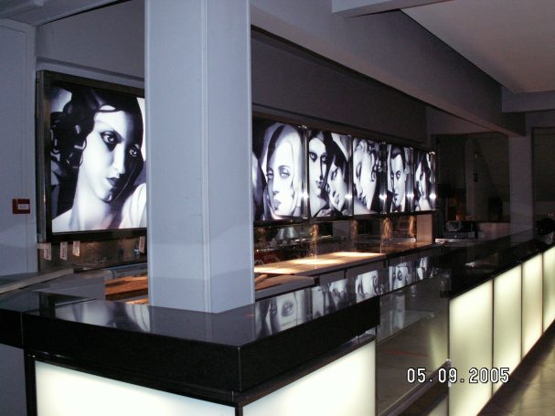 Decoración de un restaurante con pantallas mostrando rostros en blanco y negro.