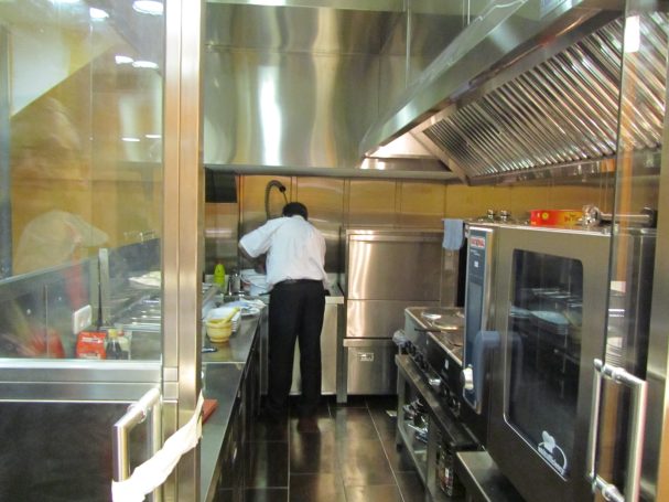 Cocinero trabajando en una cocina industrial con equipo de cocina profesional.