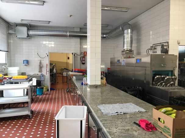 Cocina industrial con mesas de trabajo y equipo de limpieza a la vista.